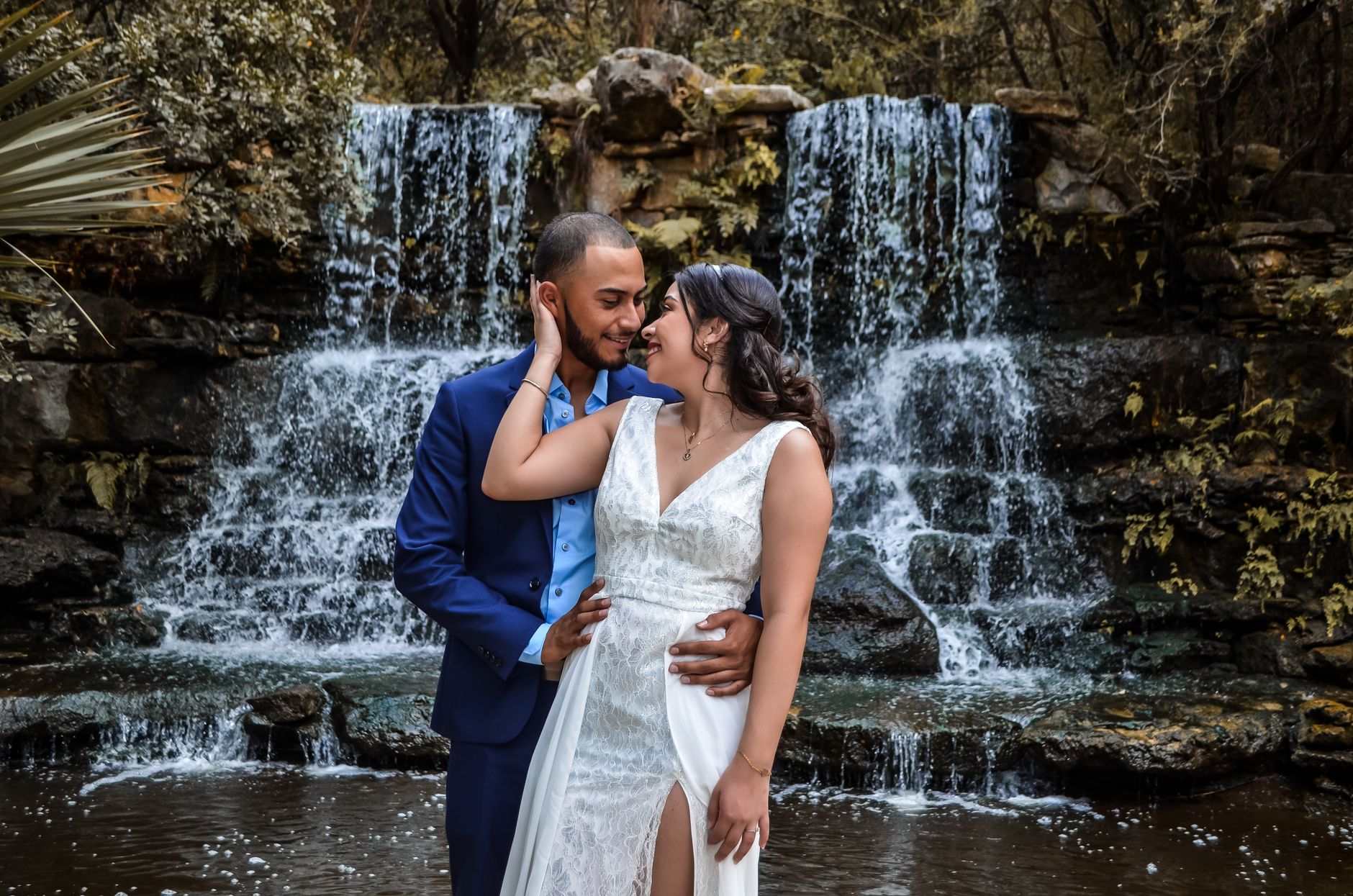 Couple in wedding attire by a peaceful waterfall